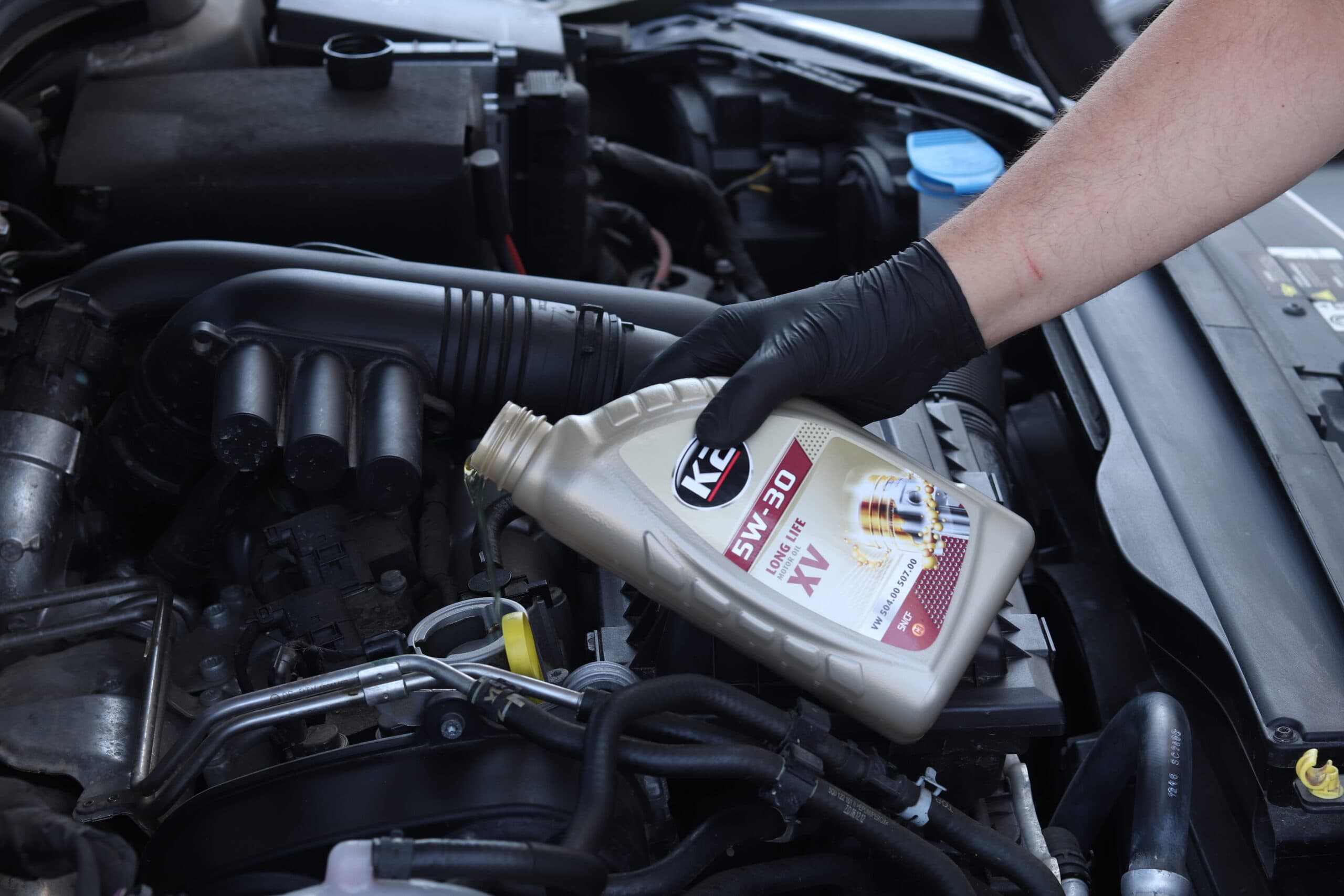 Mechanik wlewa nowy olej silnikowy podczas serwisu samochodu.